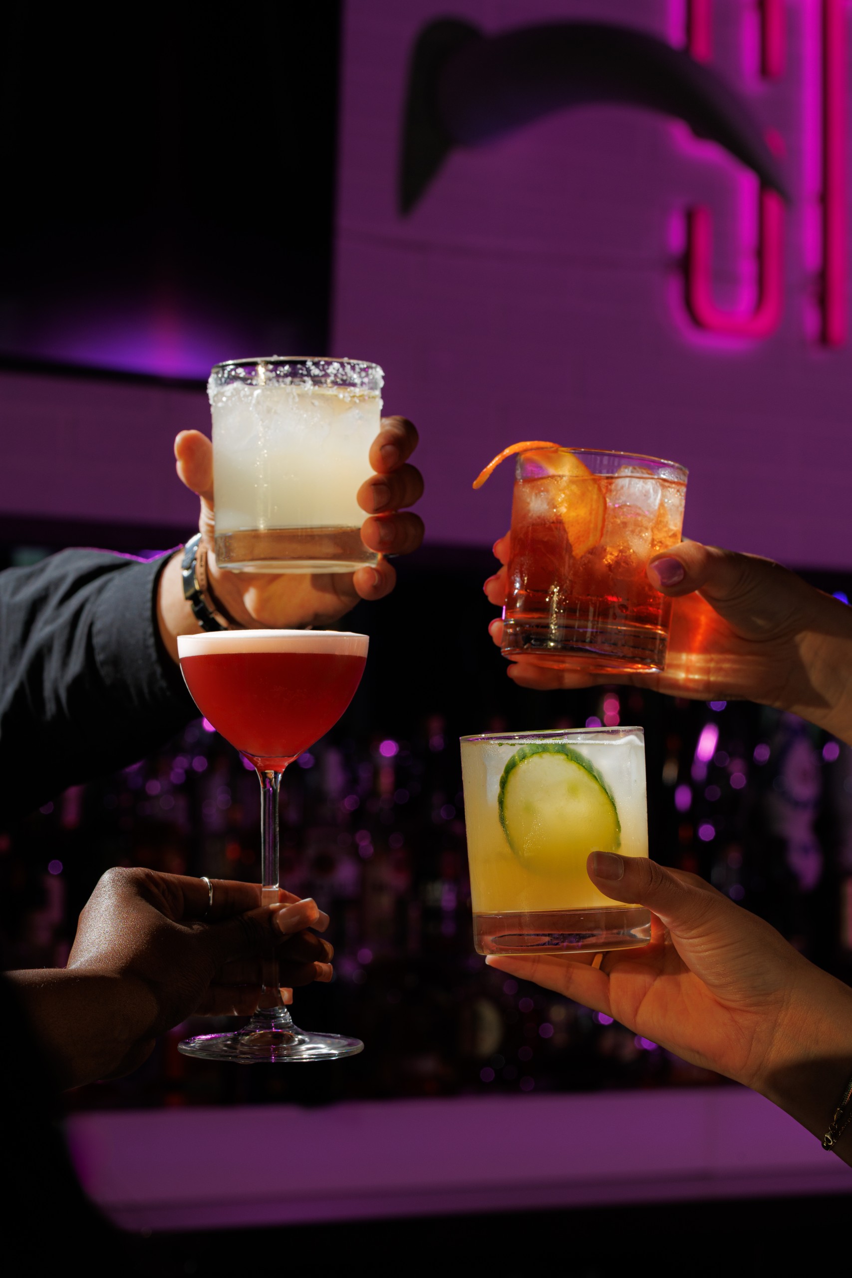 4 people holding up various STK Cocktails