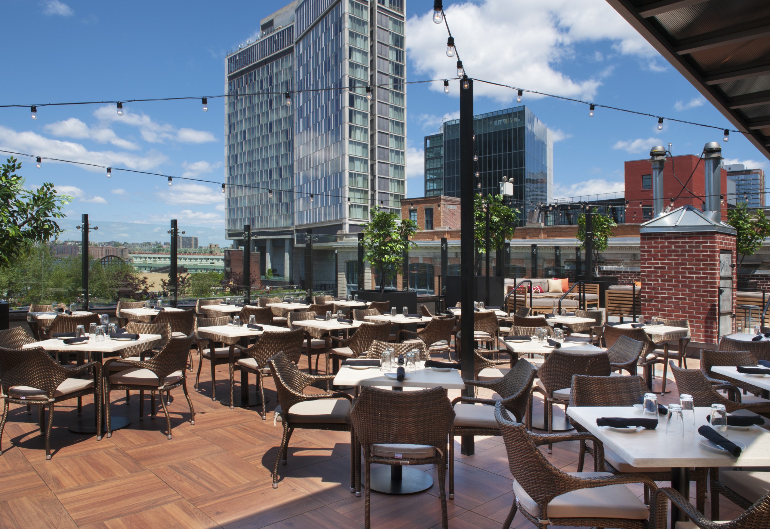 STK NYC rooftop location, tables and chairs under a sunny sky with a tall building in the distance
