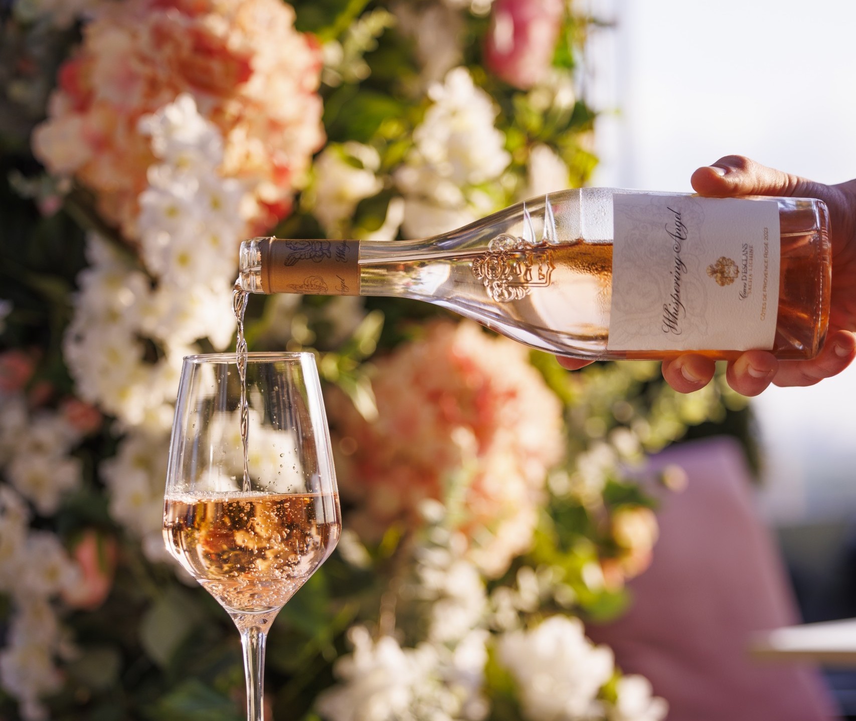A bottle of Rose being poured into a wine glass