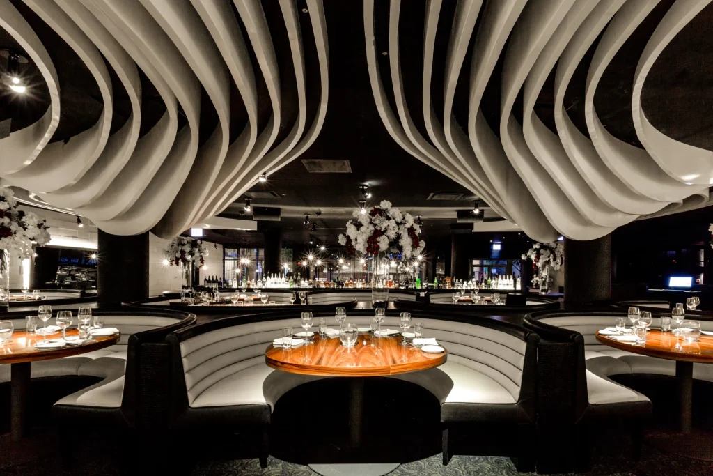 Interior of STK Chicago with large ceiling display. Circular booth seating